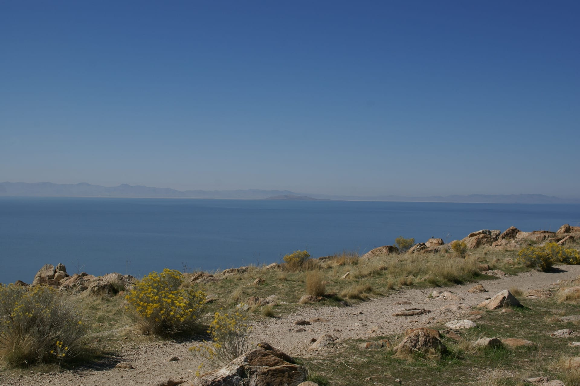 Great Salt Lake seen from a rocky hillside on Antelope Island, flat blue water reaching to distant mountains