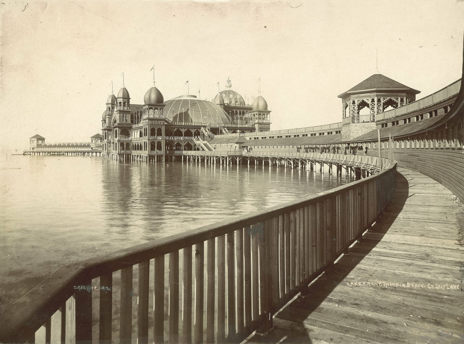 Saltair Pavilion, a domed resort built on piers, standing over Great Salt Lake in the 1890s at the end of a long wooden boardwalk