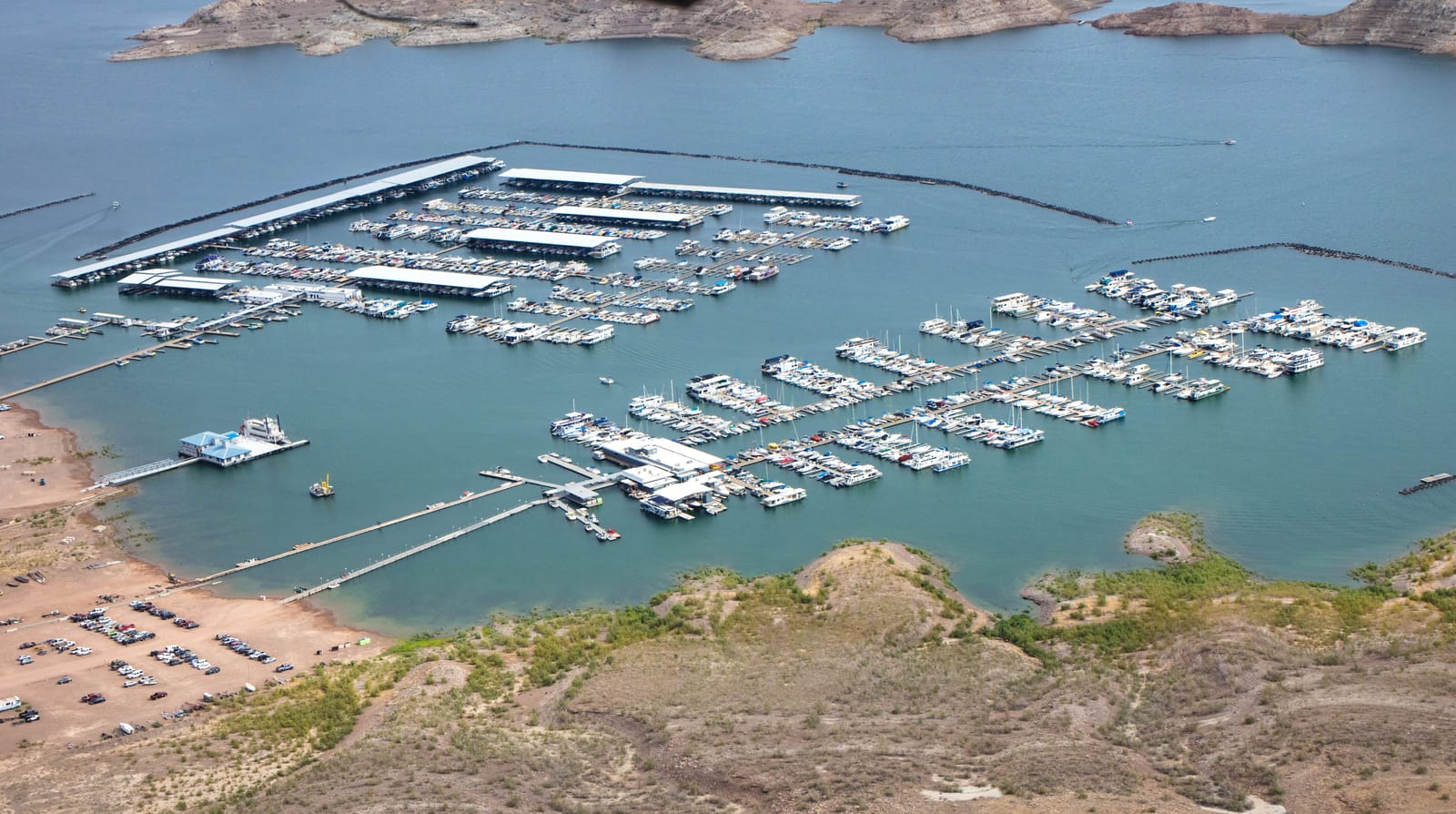 Aerial view of the marinas at Hemenway Harbor, rows of docked boats in blue-green water beside a bare desert shoreline